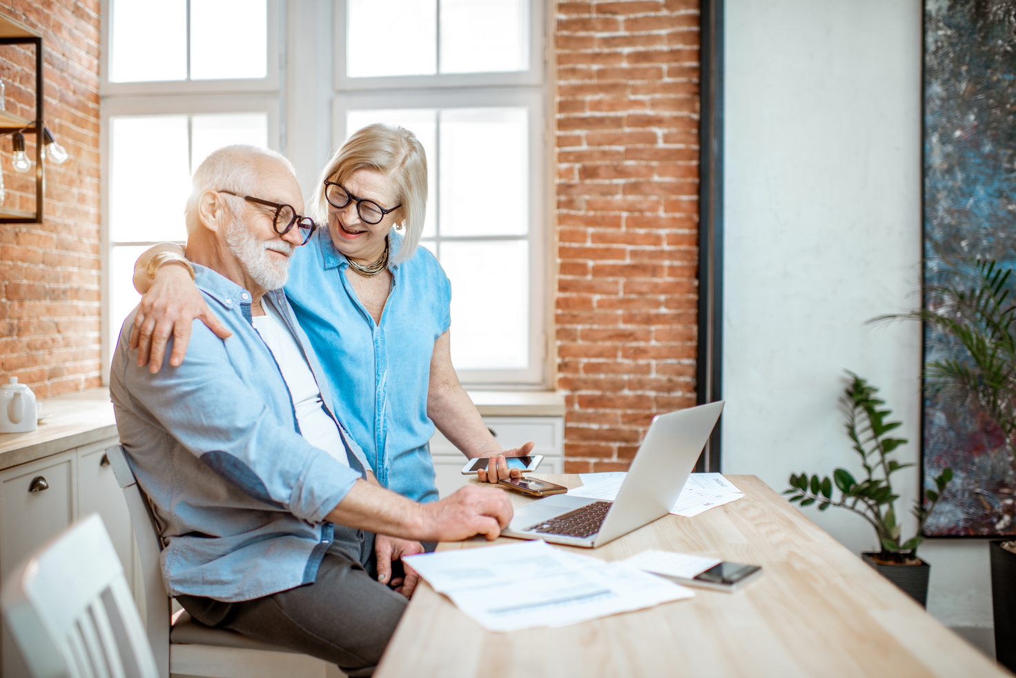 Senior couple sitting with laptop trying to figure out financing. 